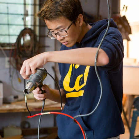 Male high school student fusing wires A student fuses wires together.